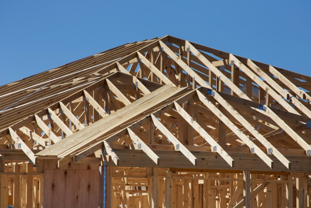 House under construction with timber wall framing and roof trusses
